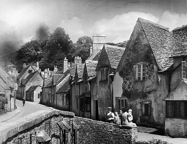 A family takes a rest on a stone wall in a Cotswold village in Gloucestershire