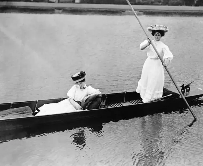 : Fashion of 1919 with women in Edwardian dress punting on a lake Clothing : Fashion of 1919 with women in Edwardian dress punting on a lake Clothing