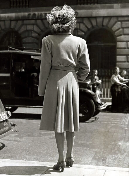 Fashion 1940s Model with her back to the camera wearing a pleated coat with doleen sleves