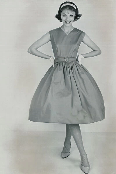 Fashion 1950s Model wearing a pinafore dress with a full skirt and white gloves