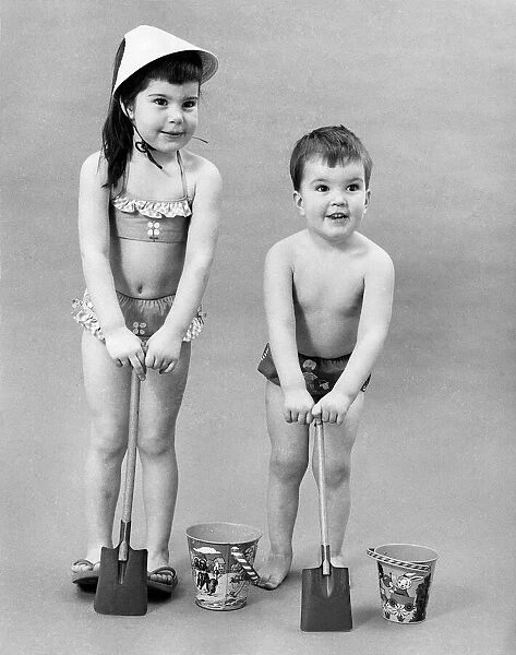 Fashion 1960s. Children play with bucket and spade in their swimwear