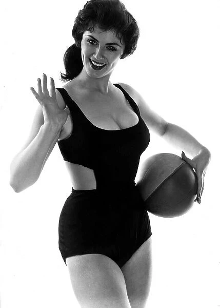 Fashion July 1958 Model from 1950s wearing a black swimsuit holding ball