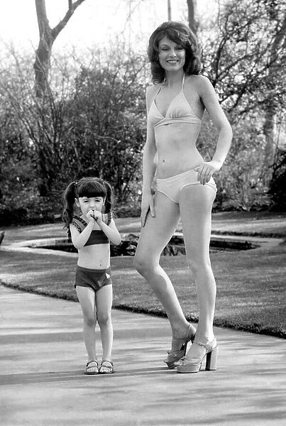 Fashion scene from Woolworth s. Woman wearing a bikini standing i n the park with a