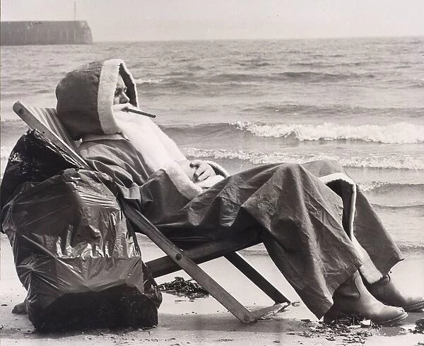Father Christmas resting in a deckchair besides the sea at Scarborough May 1978