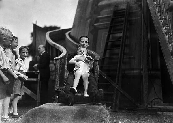 father and young son enjoy a ride on the Helter Skelter at the Tolworth Fun Fair in 1934