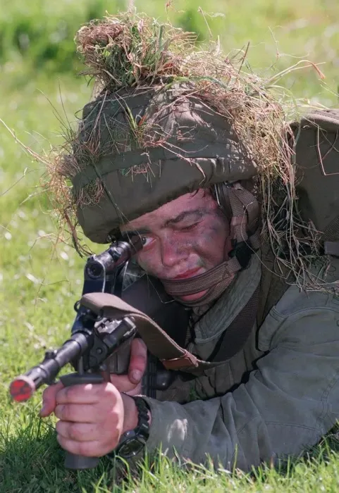 Framed Print : February 1999 Soldier in camouflage with grass on his helmet laying on the ground