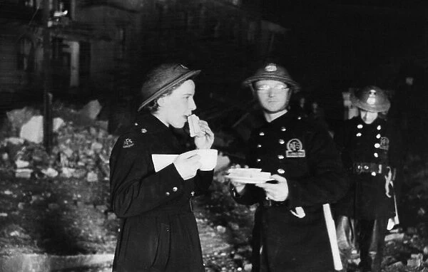 A female A. F. S. driver eating sandwiches by the light of a small fire during the Second