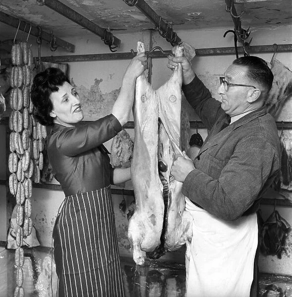 A female butcher seen here at work in her shop with her colleague. 1963