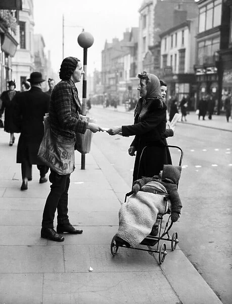 A female newspaper seller in Liverpool, selling a copy of the Daily Post to a mother in