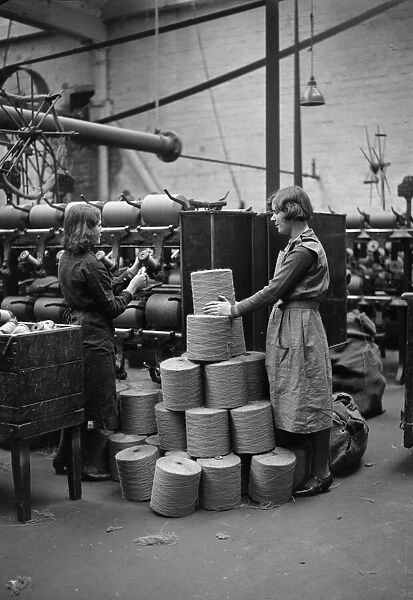 Two female workers in a flax mill with bobbins of spun flax in Dundee, Scotland