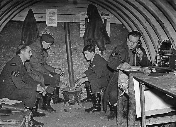 Fighter pilots of 73 Squadron RAF warm their hands on a brazier in their underground Duty