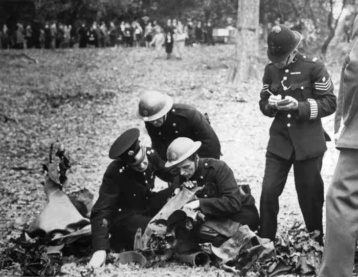 Framed Print : A fireman reading the wording on the remains of a bomb to a police officer who takes