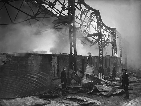 Firemen dampen down the burnt-out shell of the grandstand at St