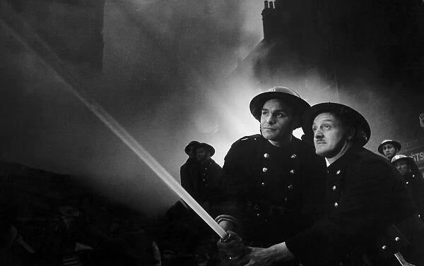 Firemen tackling fire after WW2 air raid on London. 1940s
