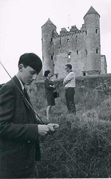 A fisherman baits his line in the shadow of thecastlweat Kouneskelly circa 1950