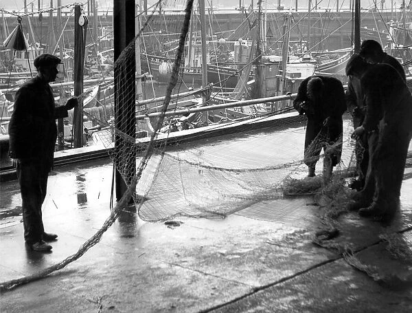 Fishermen mend their nets in the calm of the North Shields Fish Quay while a storm rages