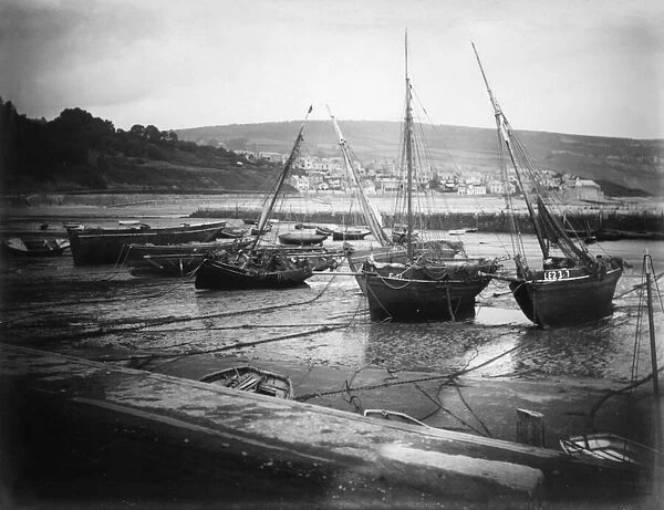 Fishing boats tied up and aground at low tide at the Cobb, Lyme Regis. Circa 1895