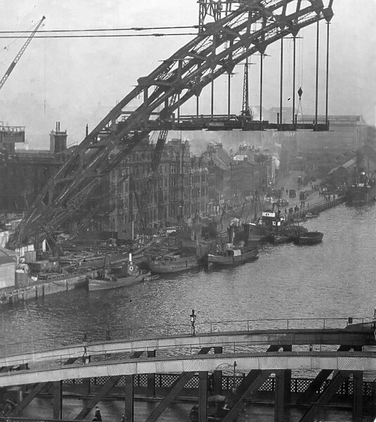 Fishing boats tied to the quay are frame by the Construction of Tyne Bridge in early 1928