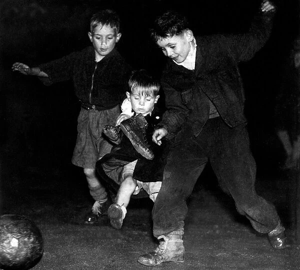 Floodlight football for young boys. 3 brothers compete for the ball