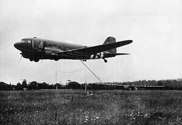 In a flower covered field in France, an American Waco CG-4 glider takes off for