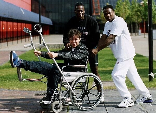 Footballer Ally McCoist of Rangers in wheelchair being pushed by Justin Fashanu