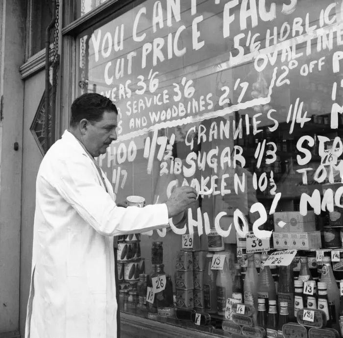 Framed Print : A Forest Gate grocer seen here painting his latest price reductions on the shop window