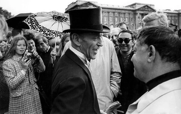 Fred Astaire returns the smiles of onlooker outside Buckingham Palace