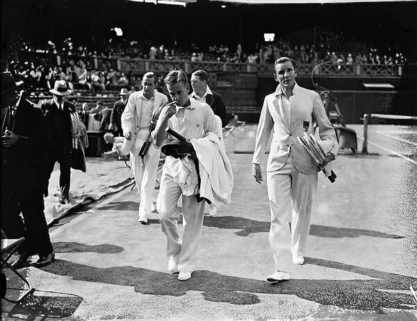 Fred Perry (right- holding tennis rackets) walking off the Centre Court at Wimbledon
