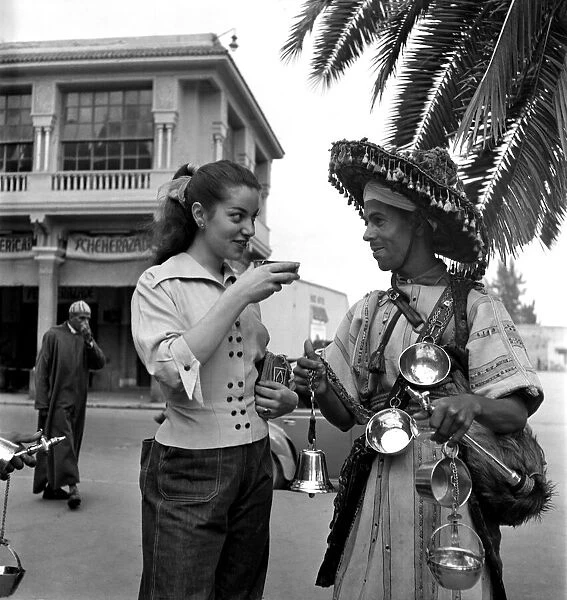 French actress buys a drink of water from a local vendor in the town of