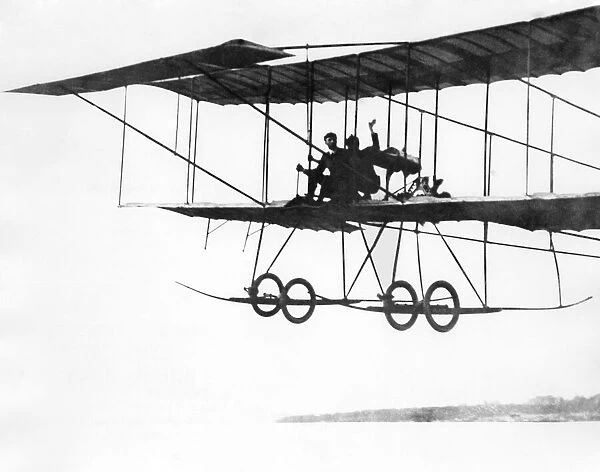 French aviator Henry Farman flying in his plane with two passengers making him the pilot