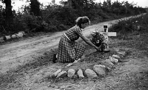 A French girl attends a British soldiers grave in France. August 1944