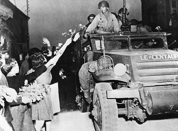 French women and children throw flowers to the French soldiers of the 2nd French Armoured