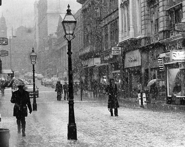 General view of King Street in the snow in Central Manchester with pedestrians walking