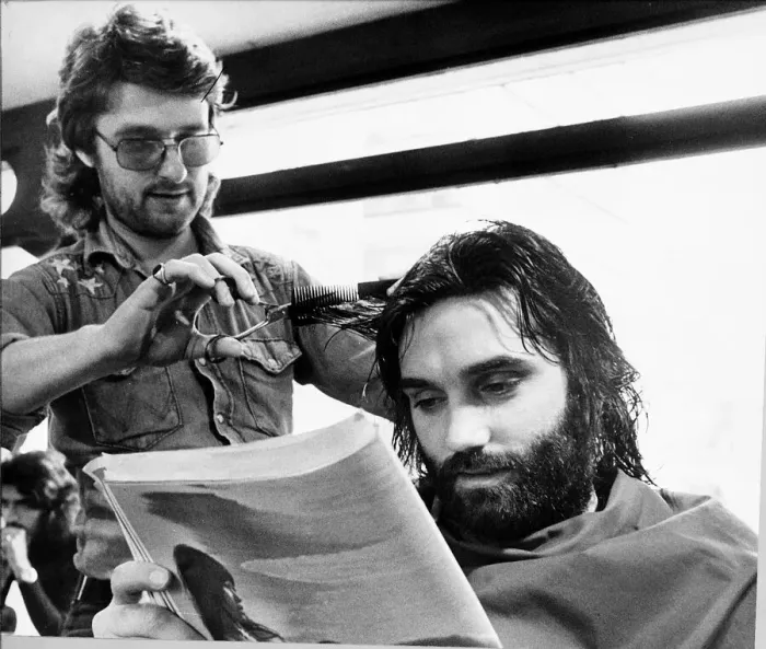 Framed Print : George Bests reads the paper whilst having his haircut May 1974 Framed Print : George Bests reads the paper whilst having his haircut May 1974