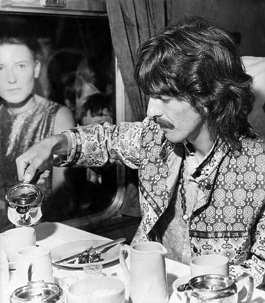 George Harrison pours himself a cup of tea in his carriage as The Beatles arrive at