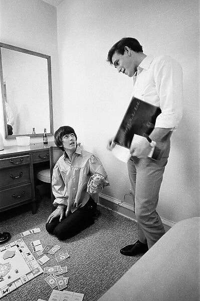 George Harrison speaks with Neil Aspinall while enjoying a game of Monopoly with singer