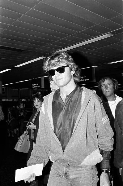 George Michael of the pop group Wham!, arriving at Gatwick airport on his return