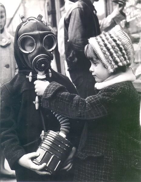 George Sizeland wears a World War Two gas mask as his sister, Marie, looks on. circa 1939