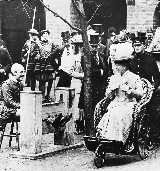 George V and Queen Mary laughing at a man in the stock during a visit to Earls Court