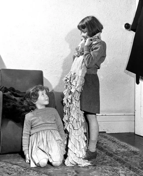 Framed Print : Girl holding up dress to show her sister December 1951