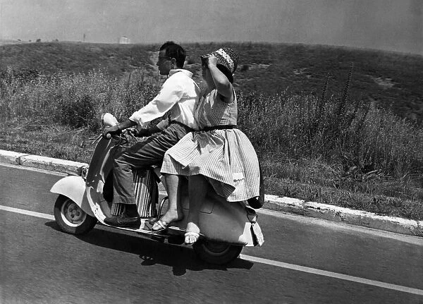 Girl riding sidesaddle on a scooter during a trip in the Italian countryside