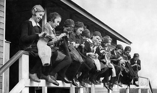 Girls at the Finnermore wood camp huts are here seen knitting sea stockings