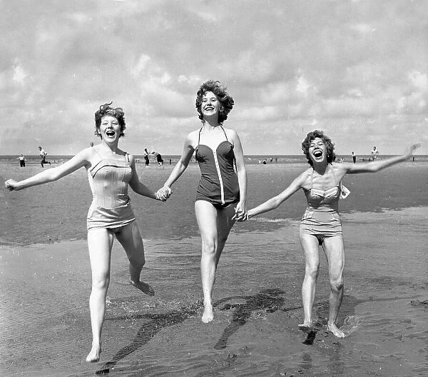 Three girls holding hands on the beach at blackpool August 1958