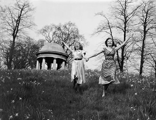 Two girls rrunning around in on a hill on a pleasant Spring day in England