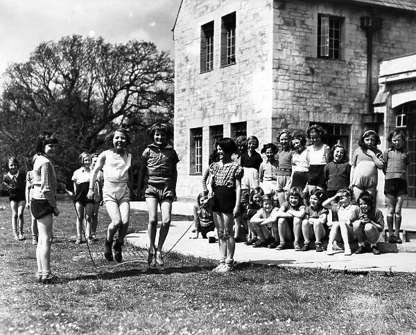Girls skipping outside on the front lawn. Circa 1950 P012106