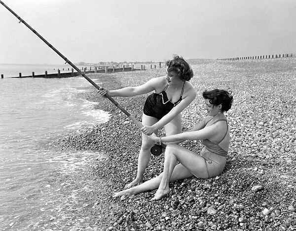 Two girls try a spot of fishing during a visit to the beach in Springtime Britain