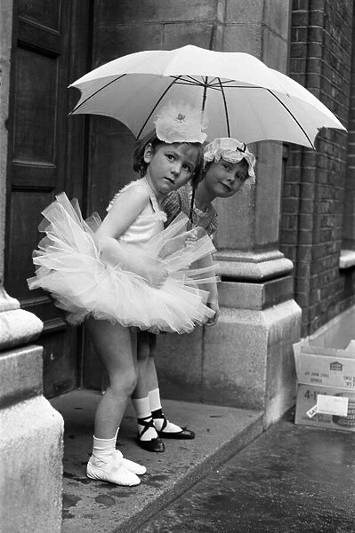 Two girls, wait for their dance teacher in the rain outside their Ballet class. 1964