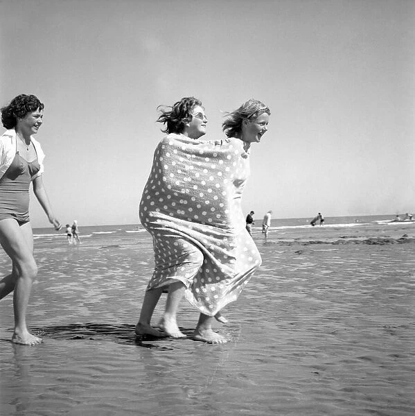 Two girls wrapped in a tent towel on the beach. June 1960 M4394
