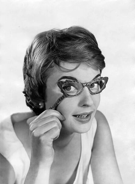 Glasses fashions. Model wears hand-held glasses. December 1957 P018651