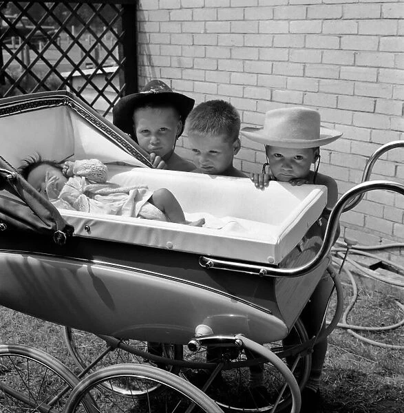 Three gloomy-faced triplet brothers aleaning over the side of a pram in the garden of